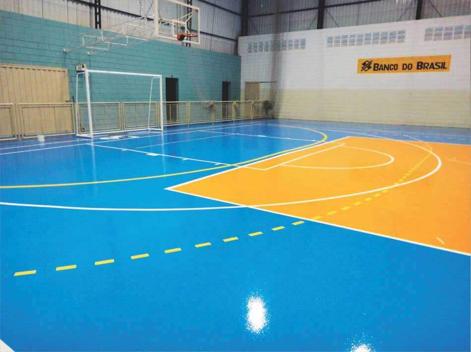 Quadra esportiva com revestimento azul e demarcações em amarelo e laranja