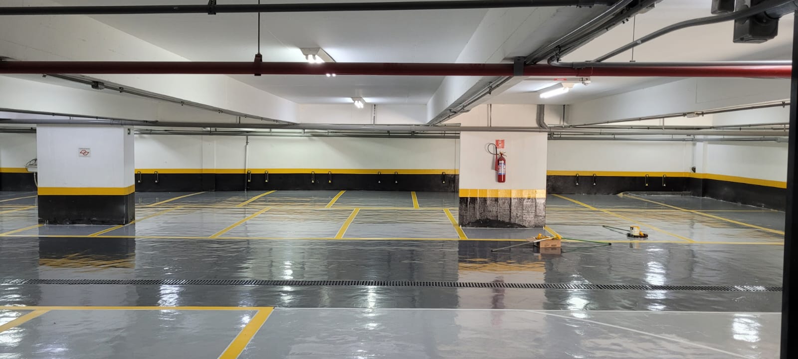 Estacionamento industrial com piso epóxi e demarcações amarelas